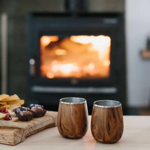 a pair of wine tumblers displayed in front of a fireplace