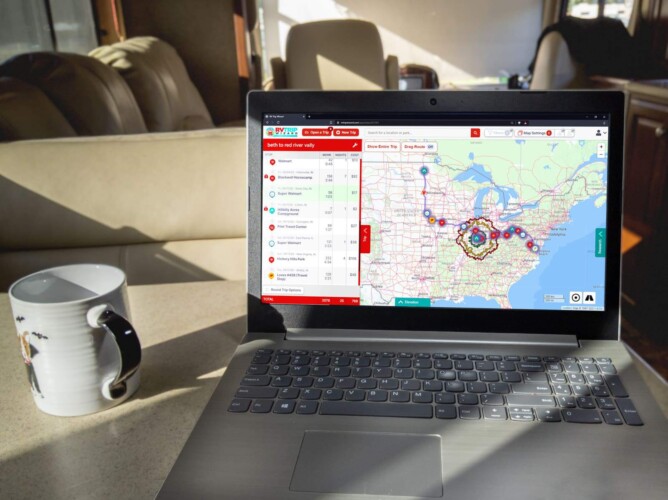 Laptop using RV Trip Wizard online with a cup of coffee on a table inside a motorhome. navigation, RV life suite, Trip Planning