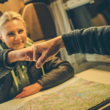 RV couple sitiing at table with map inbetween them giving approval fist bump for RV trip planning choices