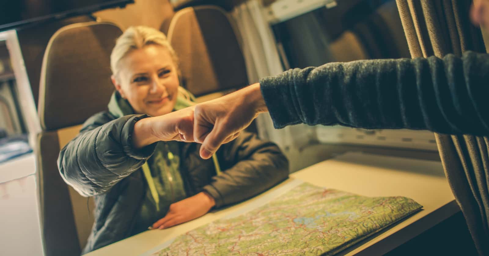 RV couple sitiing at table with map inbetween them giving approval fist bump for RV trip planning choices