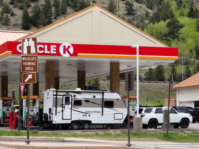 SUV towing travel trailer at gas station pump