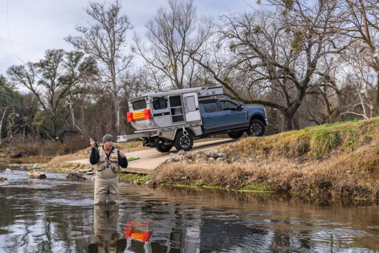 Man fly fishing with lightweight pop-up truck camper (Image: Four Wheel Campers)
